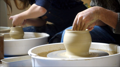 Vista ravvivinata di mani che lavorano l'argilla al tornio